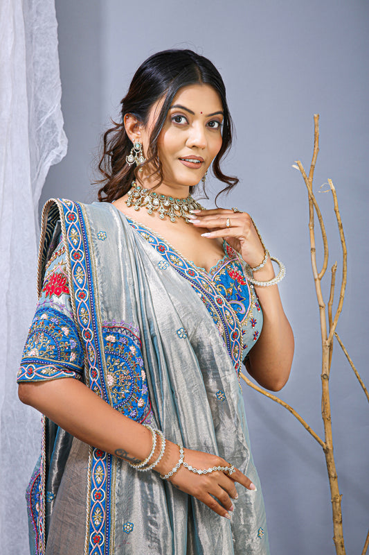Woman in traditional saree with jewelry against a gray background