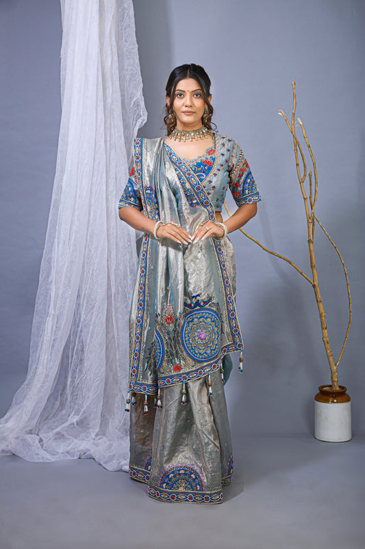 Woman in a traditional outfit with intricate patterns against a plain background